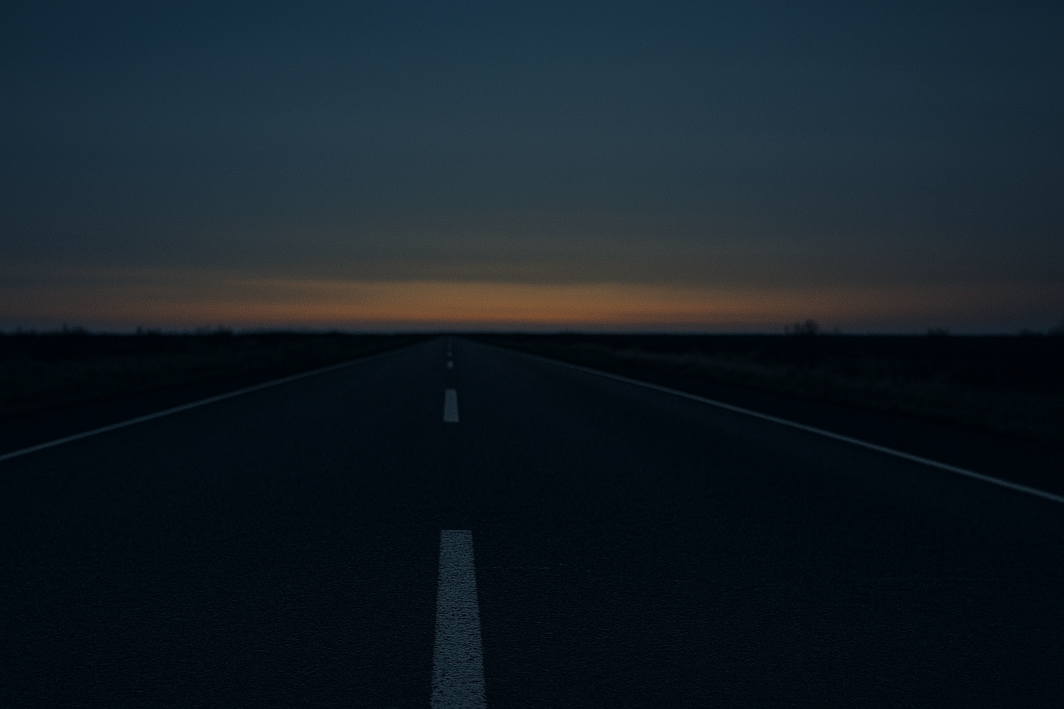 An empty road stretching to a vanishing point at dusk, shot low to the ground